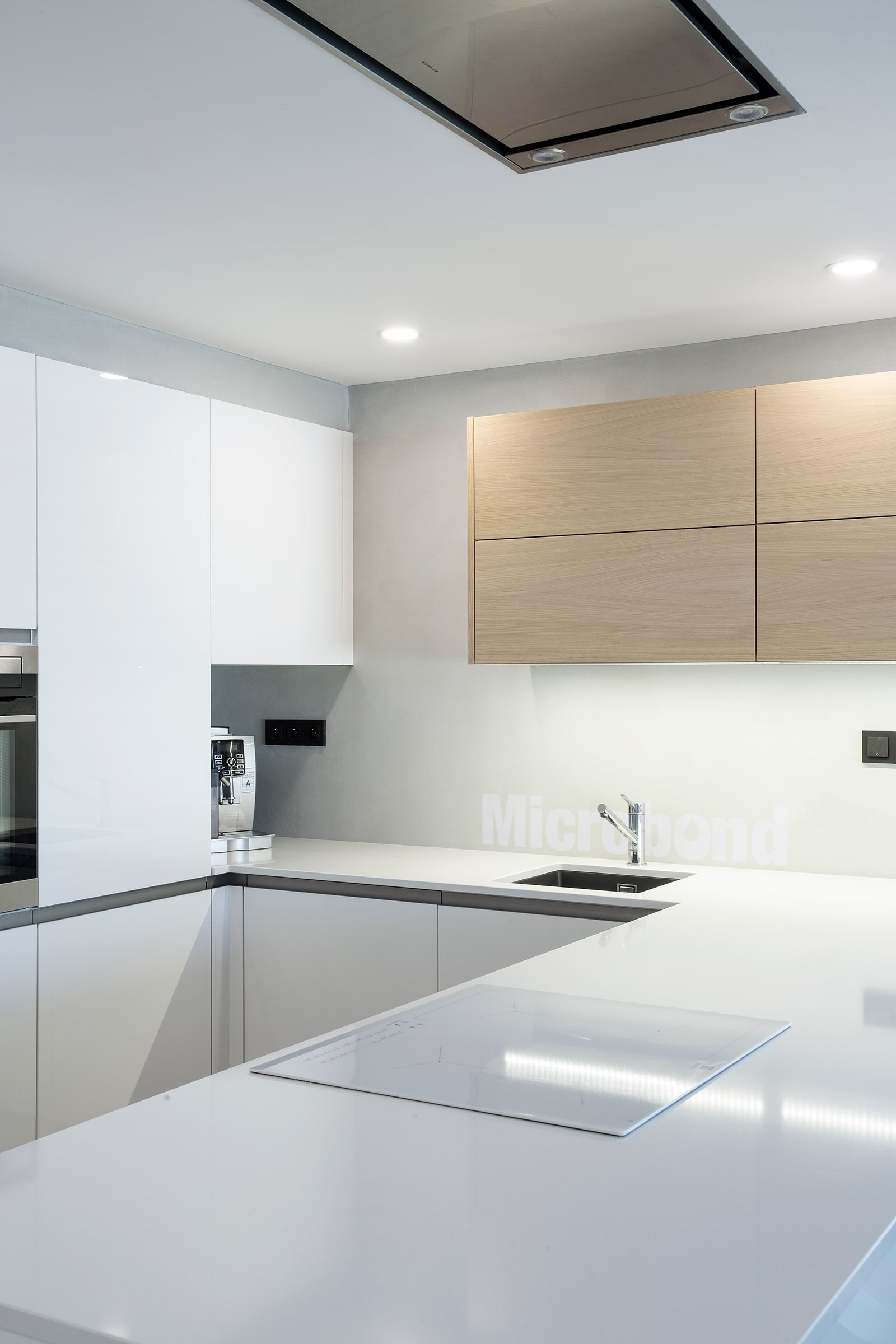 Cucina elegante e moderna, di un bianco purissimo, con parete in microcemento Microbond.