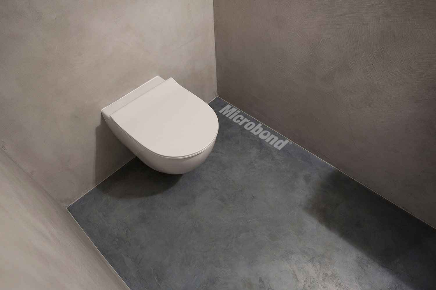 Piccolo bagno rivestito con malta decorativa Microbond su pareti e pavimento.