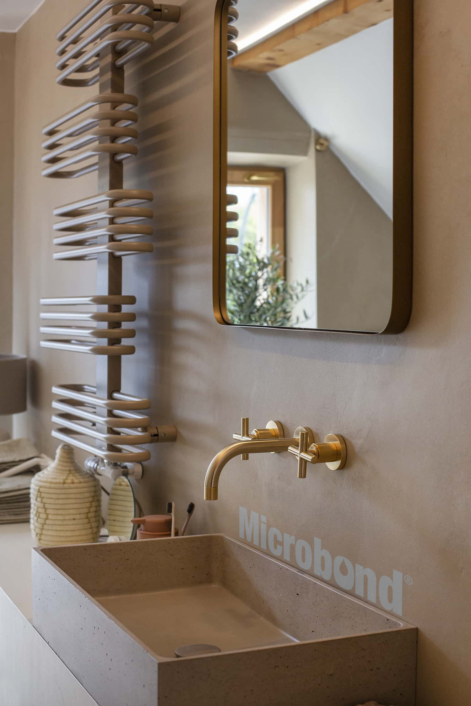 Le pareti del bagno sono rivestite con microcemento Microbond, colorato in tinta con il lavabo in pietra.