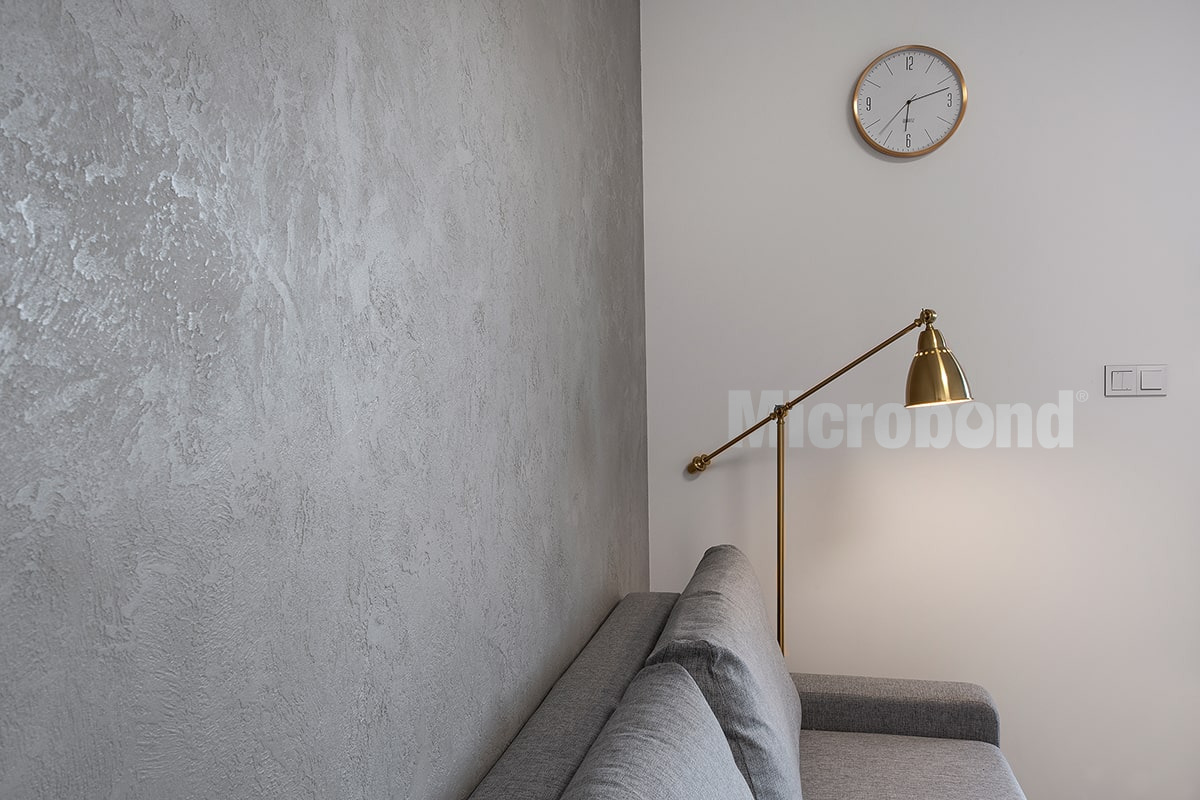 Parete del soggiorno rivestita con microcemento grigio con texture 3D.