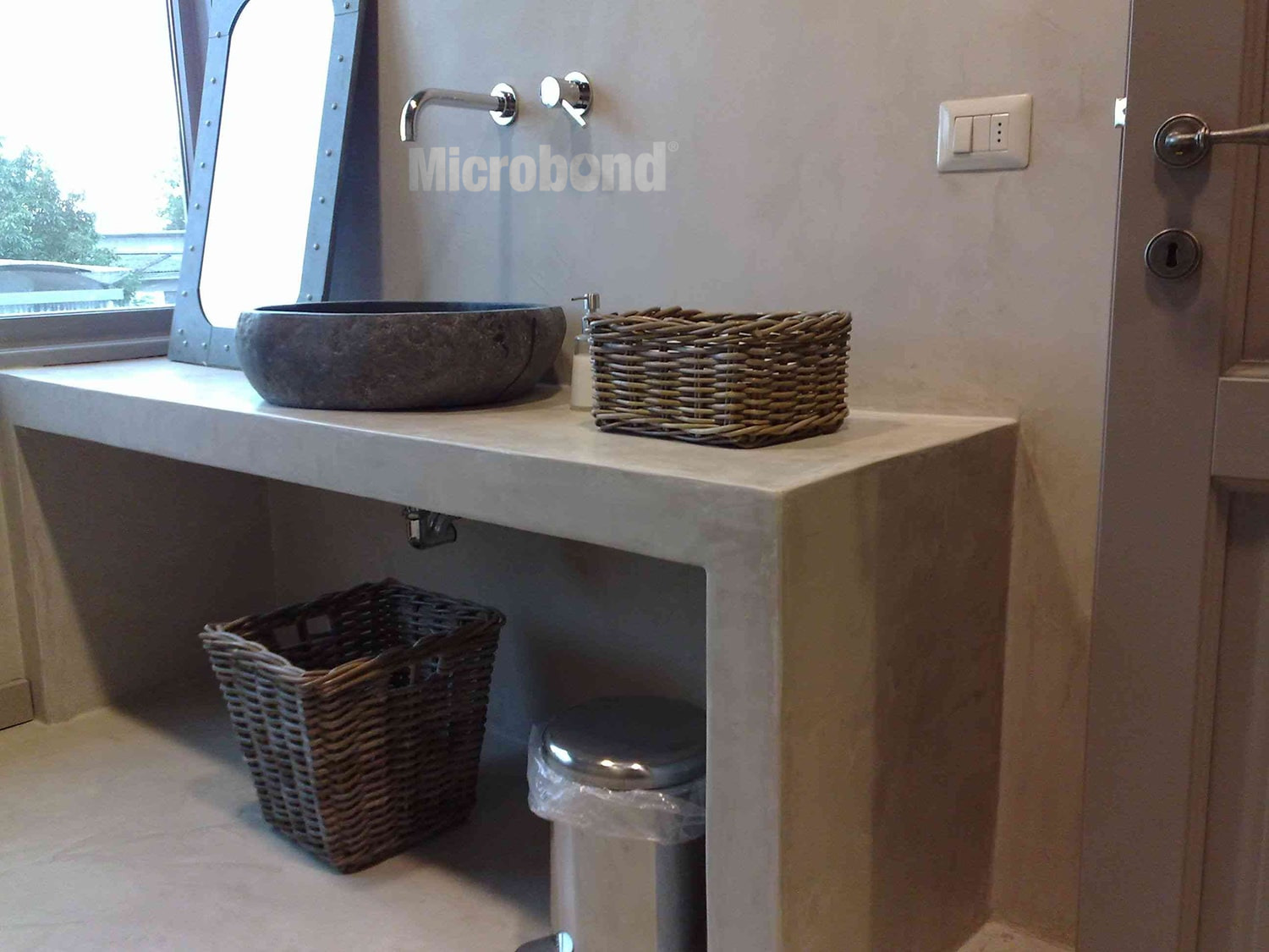 Mobile bagno e lavabo rivestiti senza soluzione di continuità con malta decorativa in stile rustico.