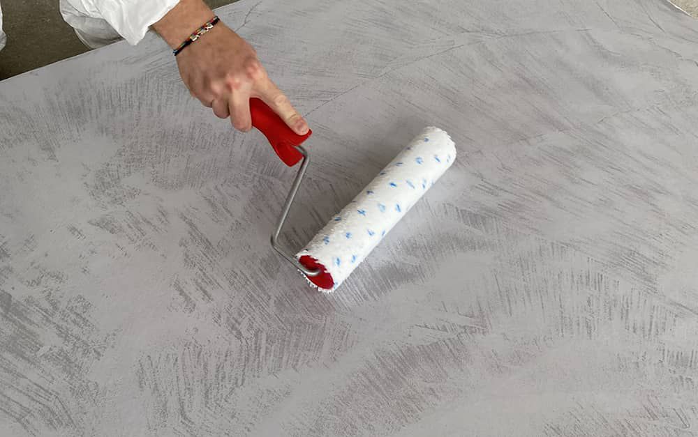 Applicazione a rullo di Cerbero Base su una superficie in microcemento grigio